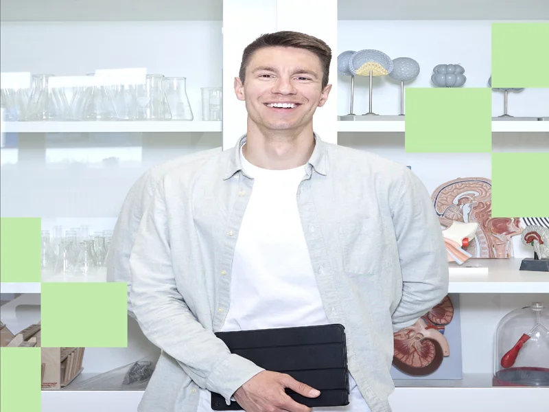Lehrkraft Sebastian Engel steht im Biologieraum vor einer Glasvitrine und schaut in die Kamera.