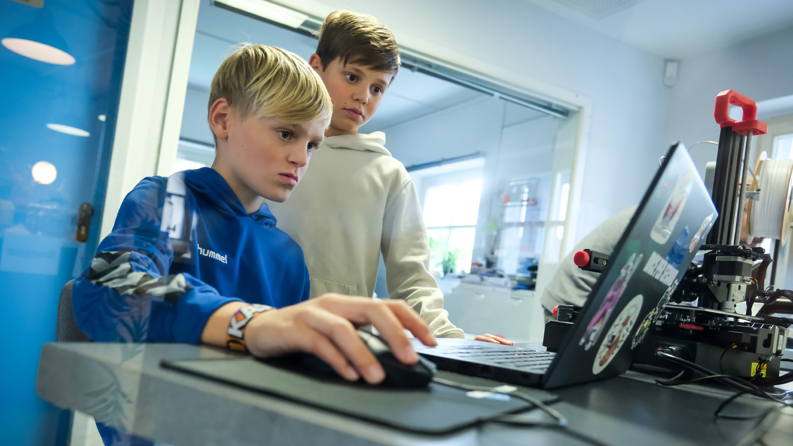 Zwei Jungs arbeiten im Bonneum konzentriert an einem Laptop.